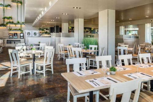 a restaurant with wooden tables and white chairs at Barceló Costa Ballena Golf & Spa in Costa Ballena