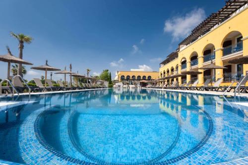 a swimming pool in a resort with chairs and umbrellas at Barceló Costa Ballena Golf & Spa in Costa Ballena