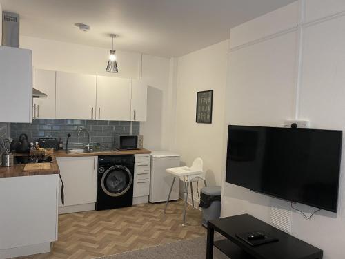 a living room with a kitchen with a washing machine at The Sand Bank - Flat 1 Abchurch Chambers BH1 in Bournemouth