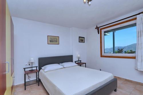 a white bedroom with a bed and a window at Villa Margarita Galini in Skopelos Town