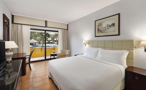 ein Hotelzimmer mit einem großen Bett und einem Schreibtisch in der Unterkunft Hilton Cairo Heliopolis Hotel in Kairo