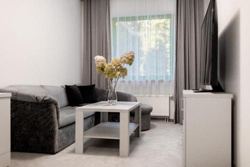 sala de estar con sofá y mesa con flores en Hotel Promenada Biznes & Wypoczynek, en Radom
