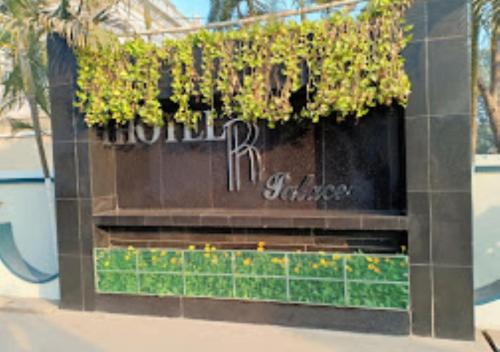 un panneau sur un bâtiment avec des plantes sur celui-ci dans l'établissement Hotel R.K.Palace Jharkhand, à Pākaur