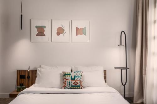 a bedroom with a white bed with art on the wall at Livingville Nine in Cairo