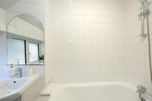Baño blanco con bañera y lavamanos en Modern Two Bedroom Flat with Free Parking Near Heathrow en Feltham