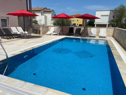 a large blue swimming pool with chairs and umbrellas at Villa Maduna 1 in Kaštel