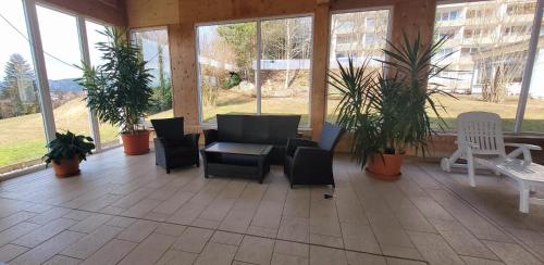 a screened in porch with chairs and tables and plants at Maria Altreichenau in Neureichenau