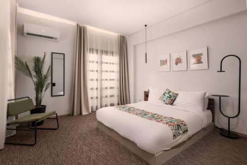 a white bedroom with a bed and a chair at Livingville Nine in Cairo
