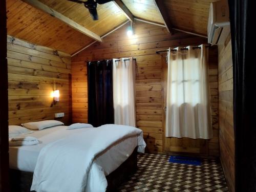 1 dormitorio con 2 camas en una cabaña de madera en Roundcube Beach Bungalows Patnem, en Patnem