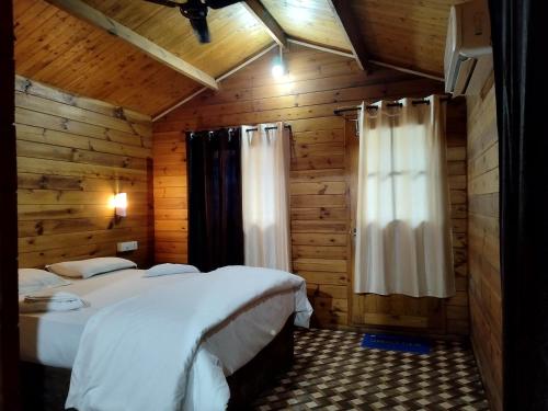 a bedroom with two beds in a wooden cabin at Roundcube Beach Bungalows Patnem in Patnem