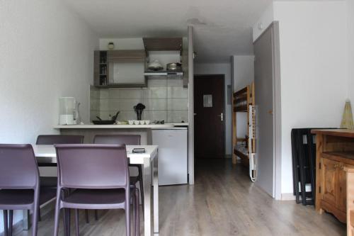 a kitchen with a table and some purple chairs at Appartement idéalement situé in Saint-Chaffrey