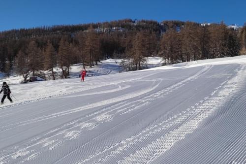 two people are skiing down a snow covered slope at Appartement idéalement situé in Saint-Chaffrey