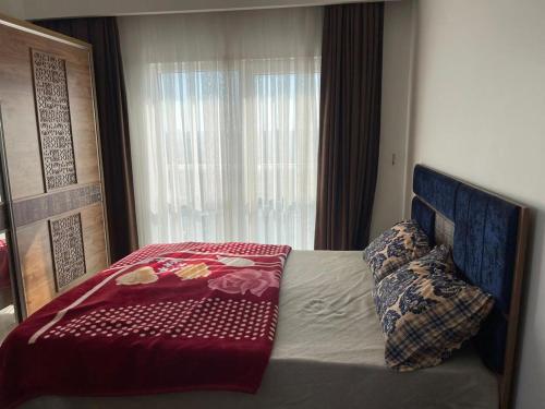a bedroom with a bed with a red comforter and a window at شقة مريحة بغرفتين وصالة في منظقة باشاك شهير - اسطنبول in Istanbul