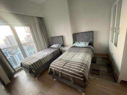 two beds in a room with a window at شقة مريحة بغرفتين وصالة في منظقة باشاك شهير - اسطنبول in Istanbul