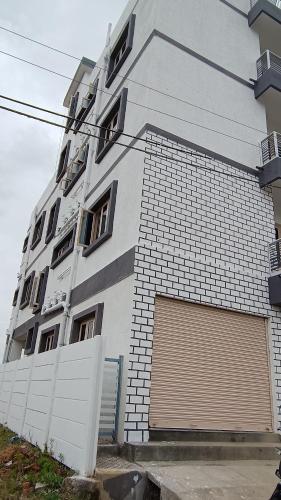 a large white building with a garage at The Heritage Serviced Apartments Mysuru in Mandya