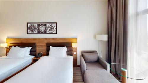 a hotel room with two beds and a chair at Premier Sofia Airport Hotel in Sofia