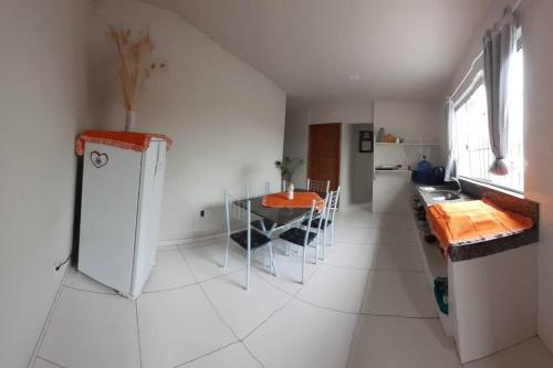 a white kitchen with a table and a refrigerator at Residencial Casa Grande- Apto 01 in Santa Cruz Cabrália