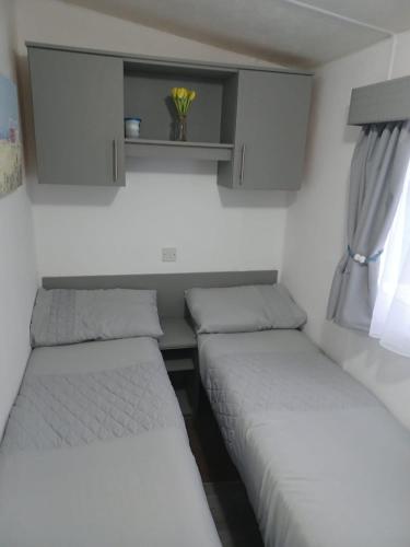 two beds in a small room with a window at 8 berth caravan Turnberry Holiday Park in Turnberry