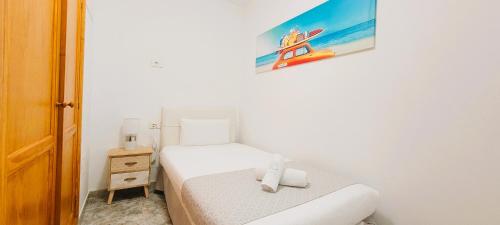 a small bedroom with a bed and a painting on the wall at Sabbia Suites Pleamar in Puerto del Carmen
