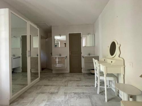 a small white kitchen with a table and a mirror at Le Pre du Moulin in Courniou