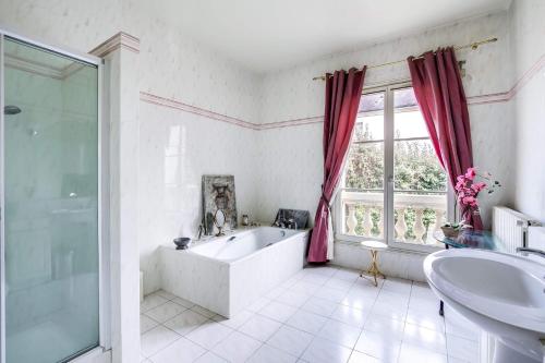 een witte badkamer met een bad en een wastafel bij La demeure d'Iris in Bougival