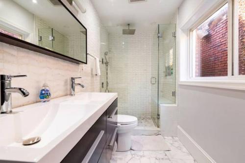 uma casa de banho com um lavatório, um WC e uma janela. em Persian Paradise Luxury with Private Parking em Washington