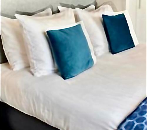 a white bed with two blue pillows on it at Hotel De la Ruïne in Valkenburg