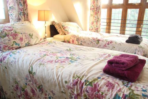 サウス・モルトンにあるWest Down Farmhouseのベッドルーム1室(花の飾られたベッド2台付)