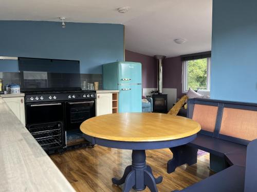 a kitchen with a wooden table and a blue refrigerator at Close to Nature Hedgehogs Lodge in South Molton