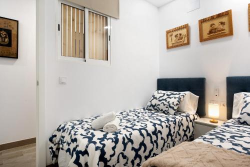 2 camas en una habitación con paredes blancas en Apartamento El Músico en Barbate