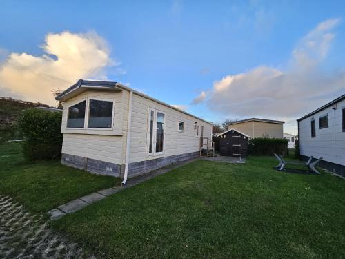 a small white tiny house in a yard at ZP 508 - Camping de Zandput in Vrouwenpolder