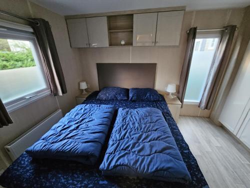 a large blue bed in a bedroom with two windows at ZP 508 - Camping de Zandput in Vrouwenpolder