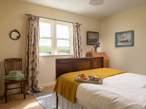 a bedroom with a bed with a tray of food on it at Stable Yard Cottage in Greenlaw