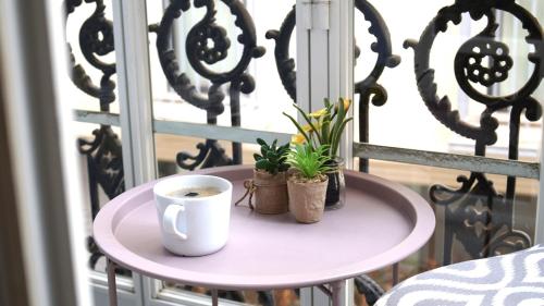 a table with a coffee cup and plants on a balcony at Fabulous City Centre Apartment - Grand Central House in Gibraltar
