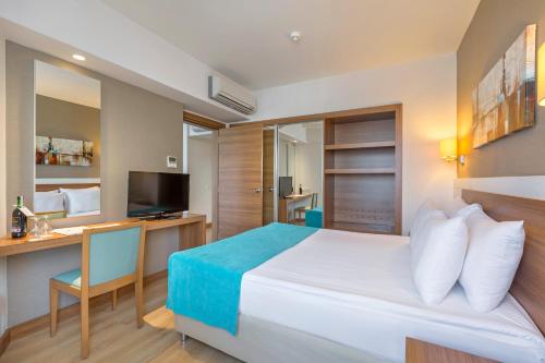 クンドゥにあるグランド パーク ララ ホテルのベッド、デスク、テレビが備わるホテルルームです。
