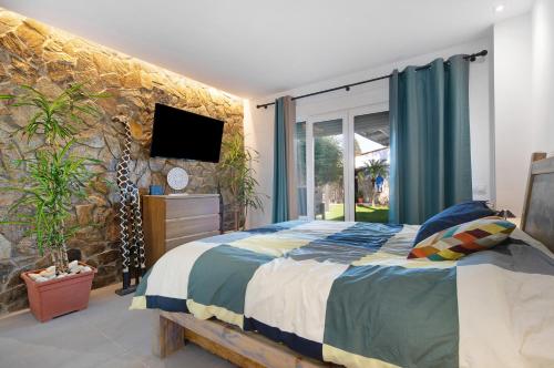 1 dormitorio con cama y pared de piedra en Villa Indie, en Chiclana de la Frontera