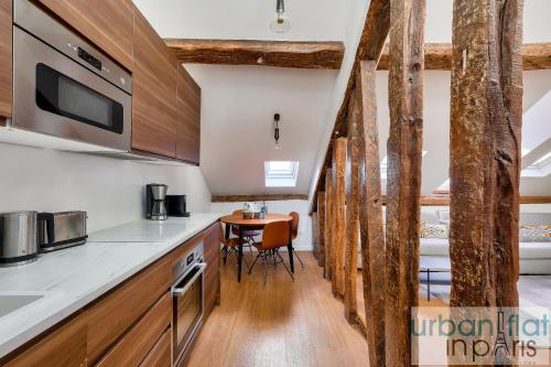 - une cuisine avec des placards en bois et une table dans une pièce dans l'établissement Urban Flat 117 - Charming 3BDR Apartment in Paris, à Paris