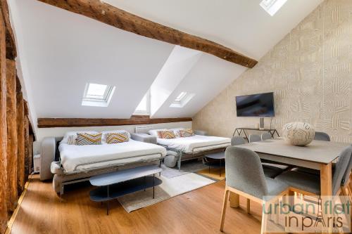 Cette chambre mansardée comprend 2 lits et une télévision. dans l'établissement Urban Flat 117 - Charming 3BDR Apartment in Paris, à Paris