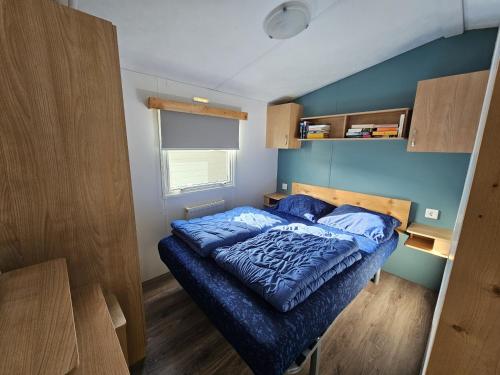 een bed in een kleine kamer met blauwe muren bij RBR 1336 - Beach Resort Kamperland in Kamperland