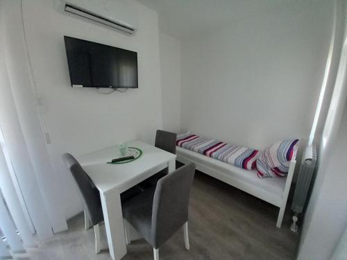 a small white room with a table and a bed at Apartmani Trifunovic in Banja Koviljača