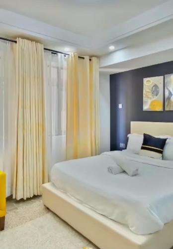 a bedroom with a large white bed with yellow curtains at The place rich in Nairobi