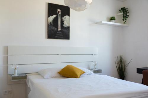 ein Schlafzimmer mit einem weißen Bett und einem gelben Kissen in der Unterkunft Pleasant City Apartment in Graz