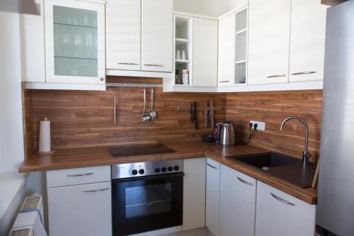 a white kitchen with white cabinets and a sink at Pleasant City Apartment in Graz