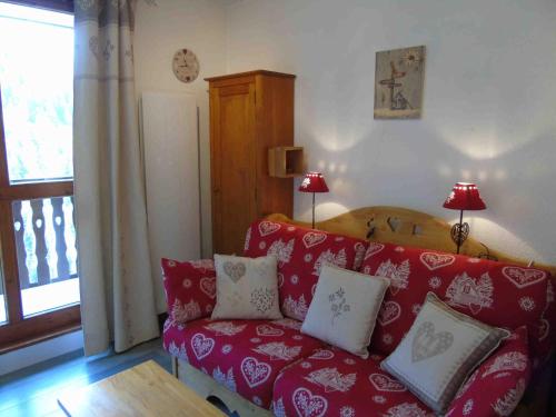 a living room with a red couch with pillows at Studio Valfréjus, 1 pièce, 4 personnes - FR-1-561-10 in Valfréjus