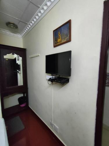 a room with a flat screen tv on a white wall at Munnar Kaippalli Budget Homestay in Munnar