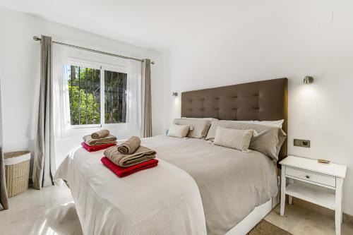 - une chambre blanche avec 2 lits et des serviettes dans l'établissement Oasis de Marbella, à Marbella
