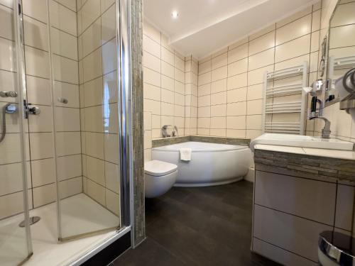 a bathroom with a tub and a toilet and a sink at Hotel Wernerwald in Cuxhaven