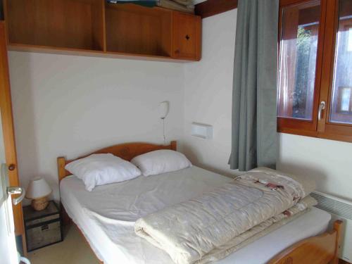 Cette petite chambre comprend un lit avec des draps blancs et une fenêtre. dans l'établissement Appartement 2 pièces + cabine, 6 pers, à Valfréjus, draps inclus, animaux admis - FR-1-561-15, à Valfréjus