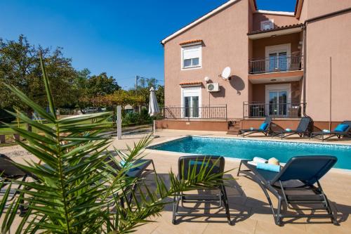 a villa with a pool and chairs and a house at Villa 1399 in Hreljići