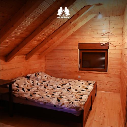 a bedroom with a bed in a wooden room at Vikendica Stevanovic in Doboj